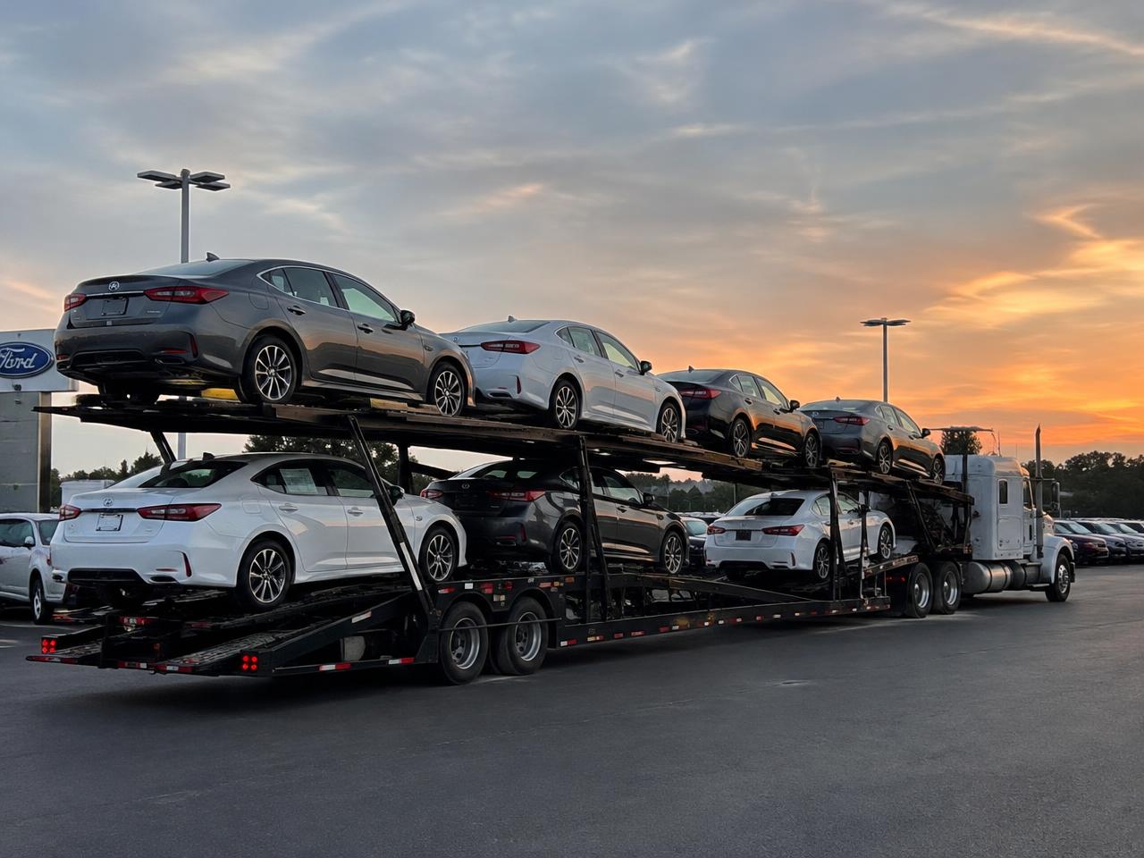 Car carrier loaded with sedans at a dealership